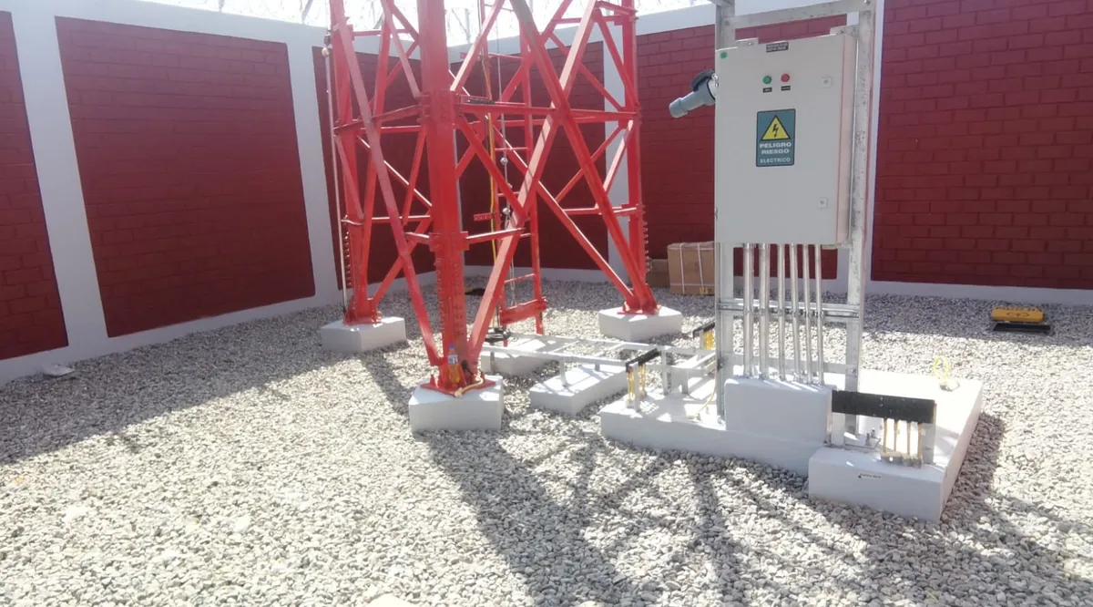 Base de una torre nueva sobre grava, con su tablero eléctrico y el cerco de ladrillo alrededor.