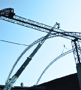Arcos metálicos de un techo parabólico en montaje, sostenidos por una grúa.