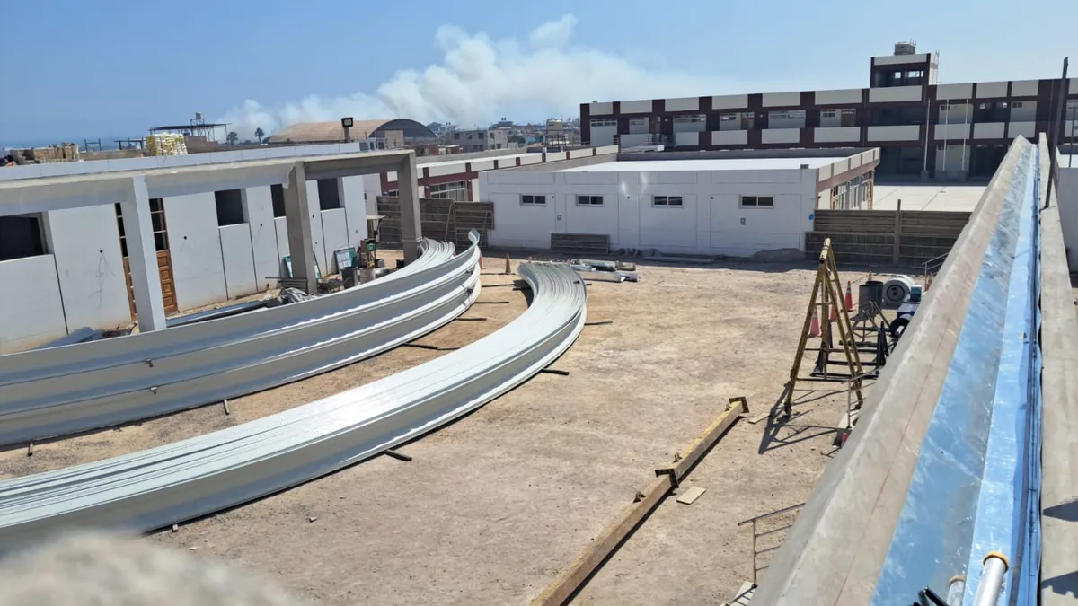 Láminas curvas de arcotecho apiladas en la azotea de una obra, listas para instalar.